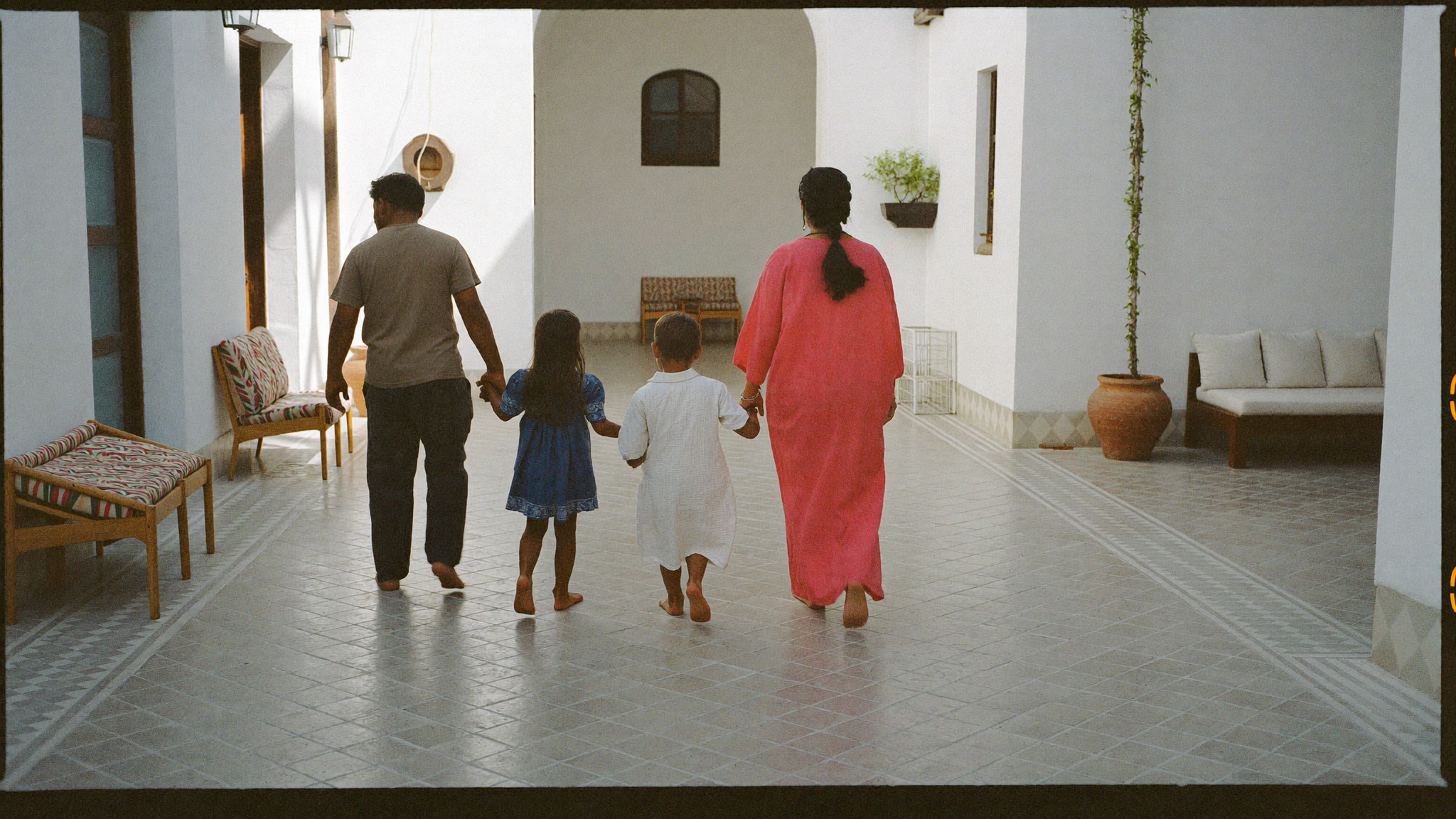 Cour ombragée d'un riad marocain avec fontaine et coussins, ambiance familiale et calme